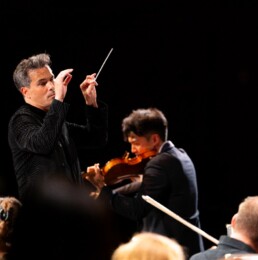 Dane Lam conducting with a violin soloist